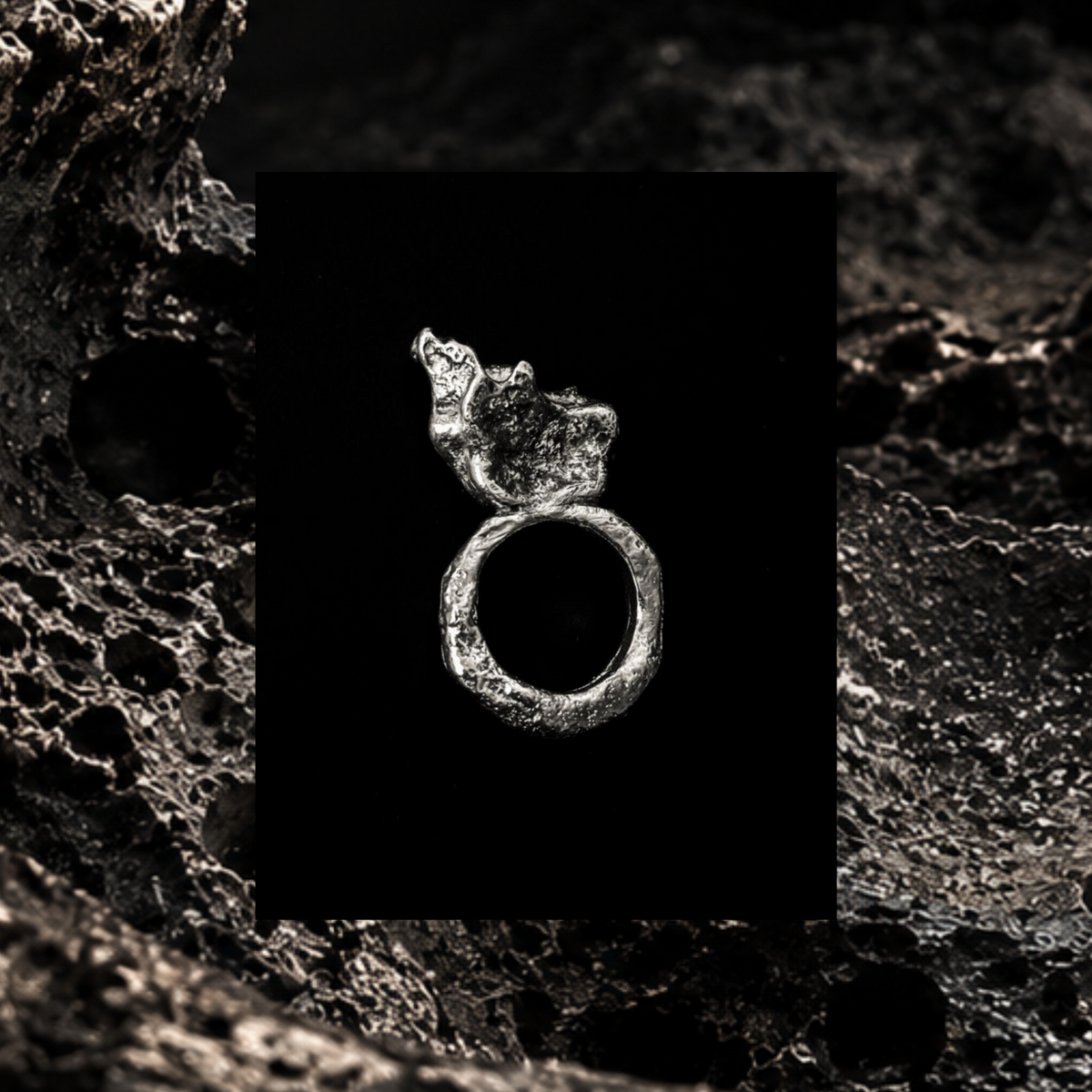 MATERIA — anello scultoreo in argento su superficie minerale porosa scura